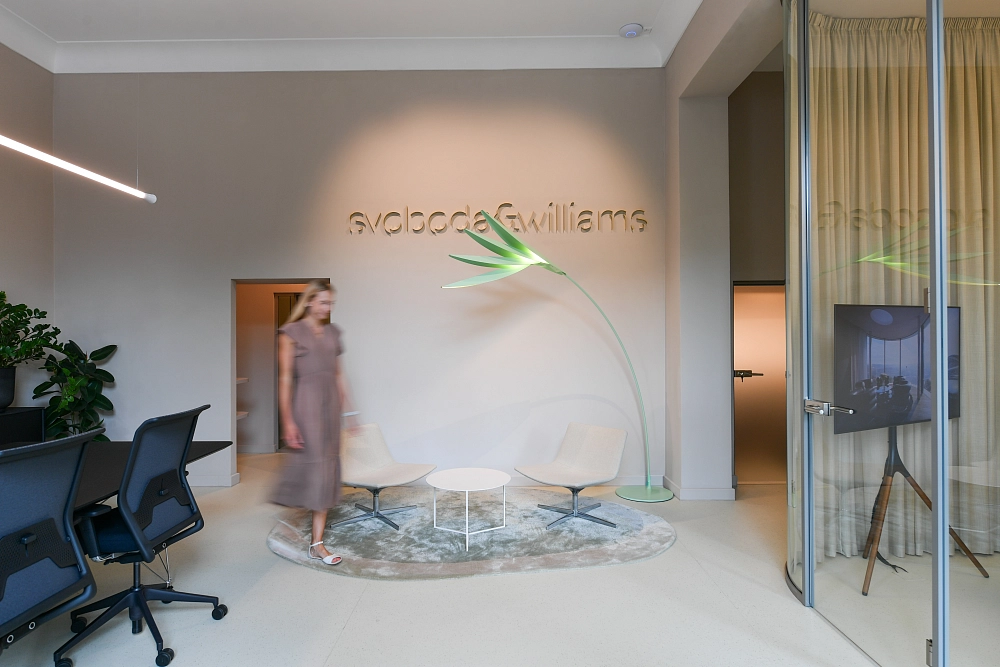 The lounge at the Karlovy Vary branch of the Svoboda & Williams real estate agency, featuring a neon logo